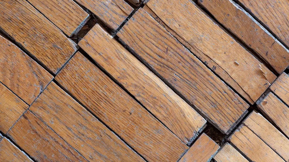 Un parquet ancien en chevrons, décapant appliqué au pinceau et lame de rasoir posée sur un chiffon